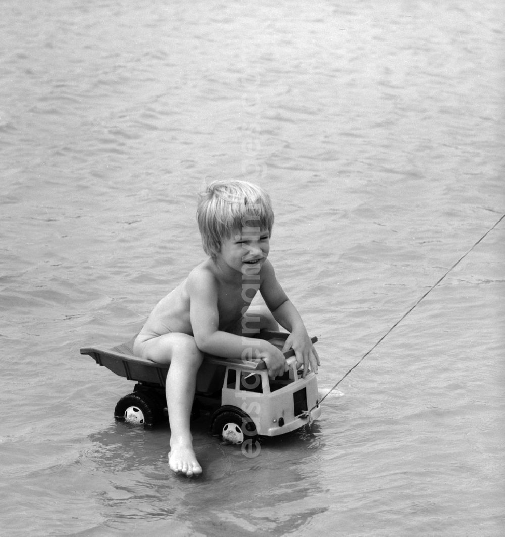 Teupitz: Boy on a plastic truck in water at Teupitzer lake in Teupitz in Brandenburg on the territory of the former GDR, German Democratic Republic