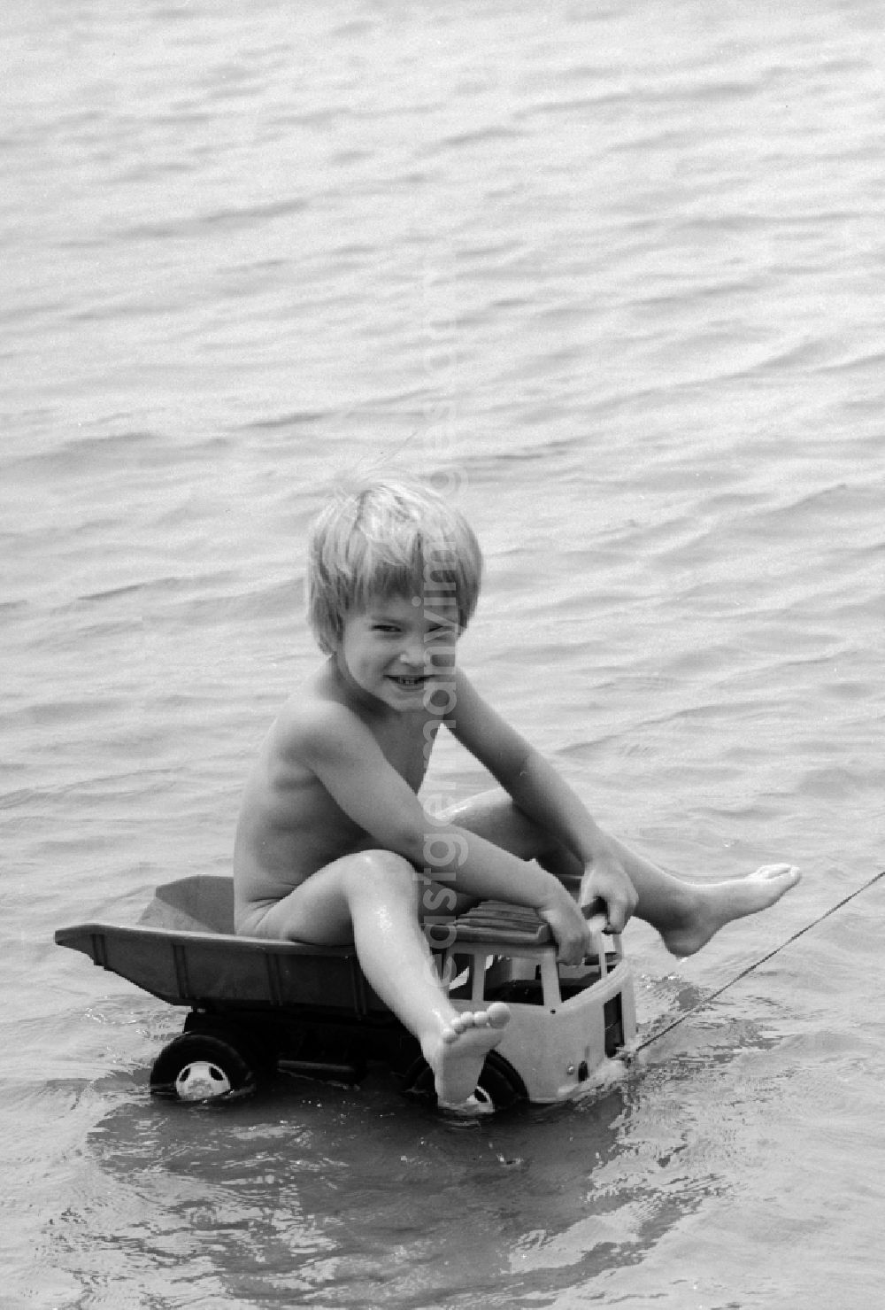 GDR image archive: Teupitz - Boy on a plastic truck in water at Teupitzer lake in Teupitz in Brandenburg on the territory of the former GDR, German Democratic Republic