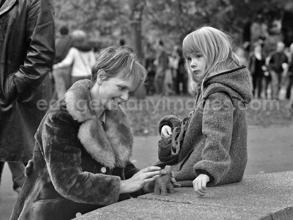 Berlin: Mother with child as a young family with a little girl in the park at Weberwiese in the district of Friedrichshain in Berlin East Berlin in the area of ??the former GDR, German Democratic Republic. The mother kneads a clay figure