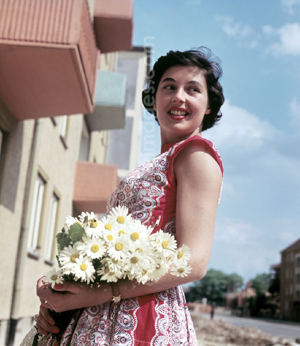 Coswig: A young woman poses with flowers in front of a newly built block of flats in Coswig, Saxony in the territory of the former GDR, German Democratic Republic