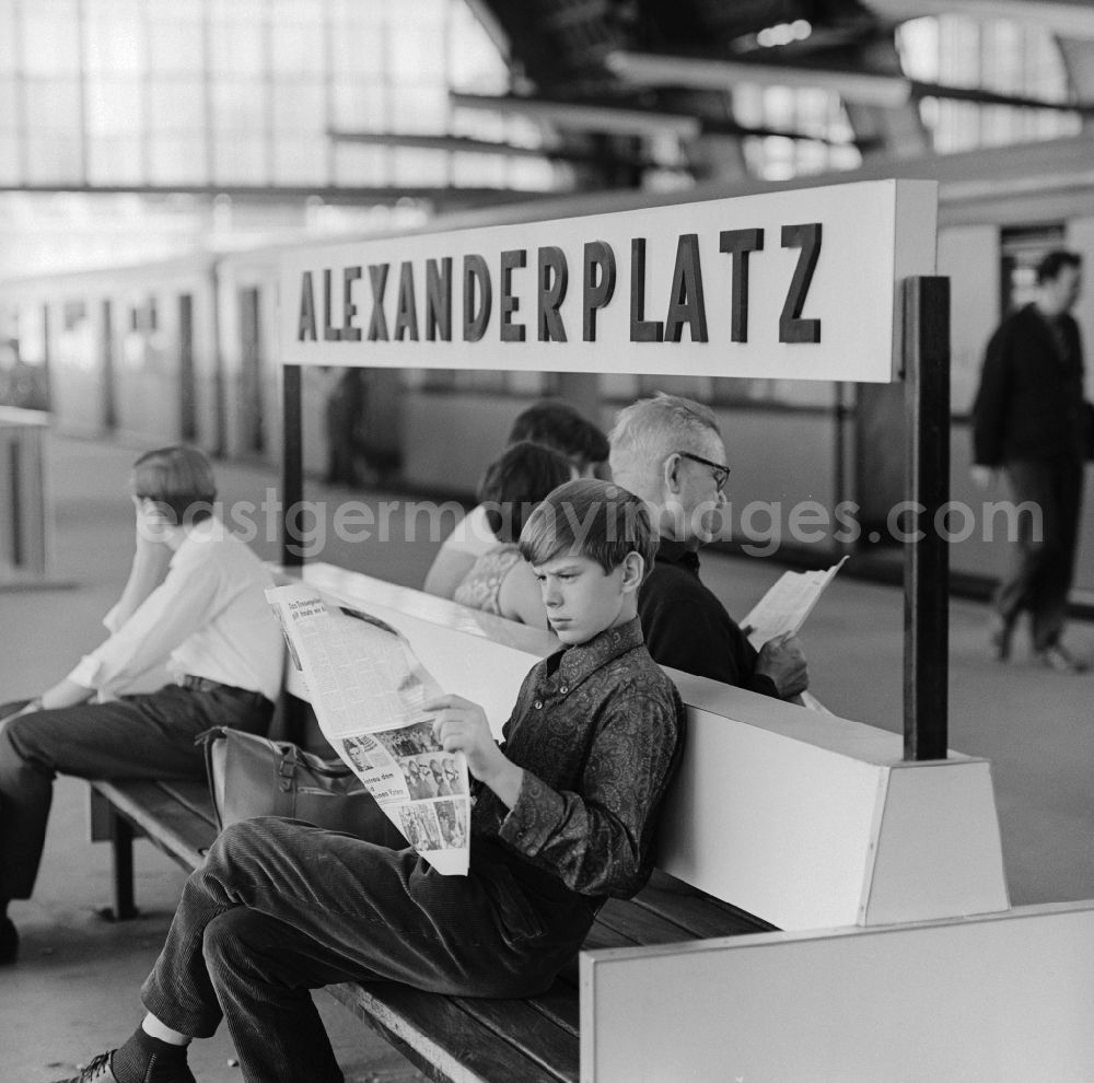 Berlin - Mitte: Boy reading a newspaper on a bench in the station Alexanderplatz in Berlin - Mitte
