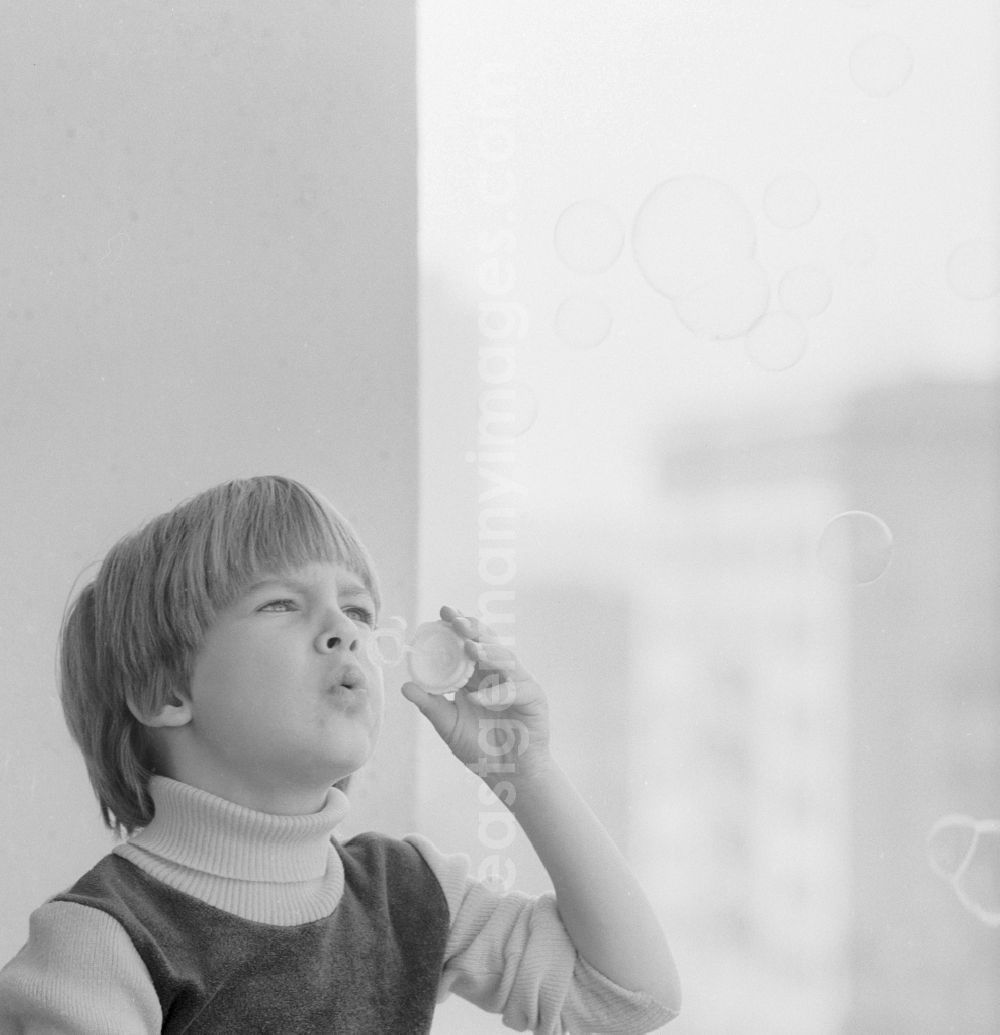 Berlin: Boy making soap bubbles on a balcony in Berlin, the former capital of the GDR, the German Democratic Republic