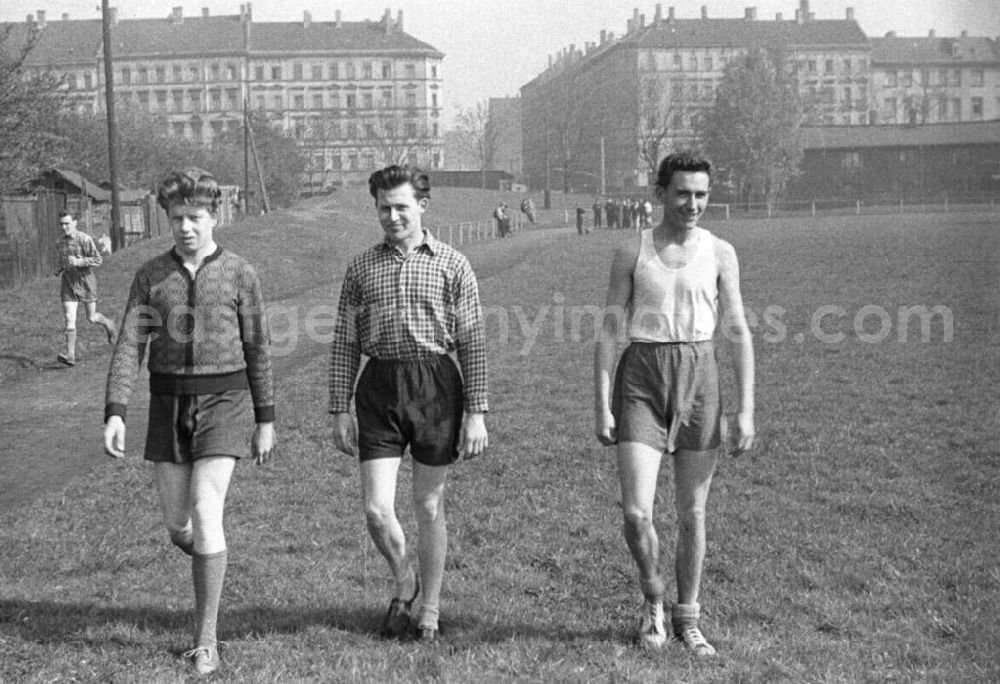 GDR image archive: Leipzig - Drei junge Männer überqueren einen Rasenplatz in sportlicher Kleidung. Im Hintergrund Häuserfront. Bestmögliche Qualität nach Vorlage!
