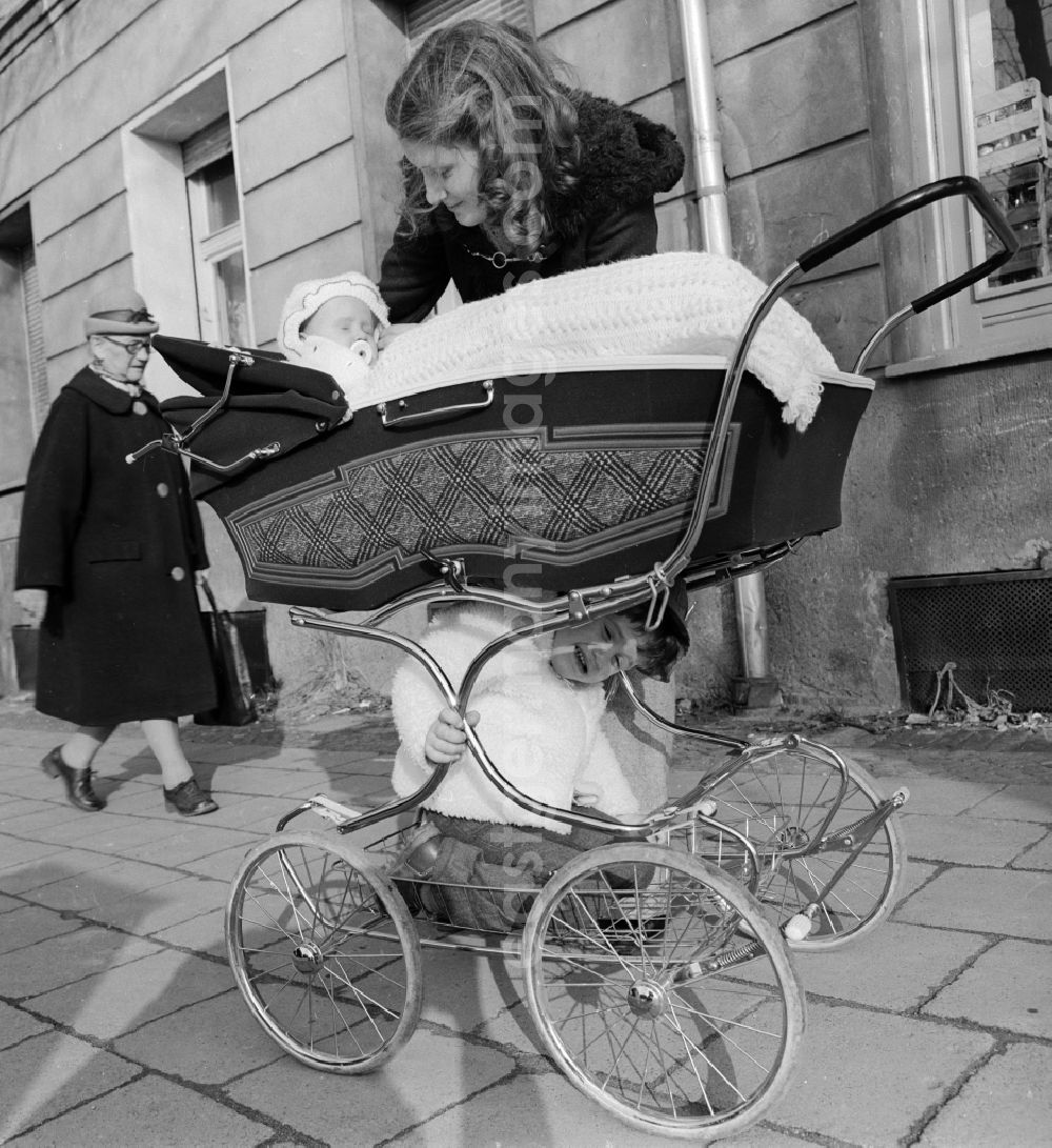 GDR picture archive: Berlin - Young mother with a pram on a walk in Berlin. Above is the baby in the basket and sits below the larger sibling