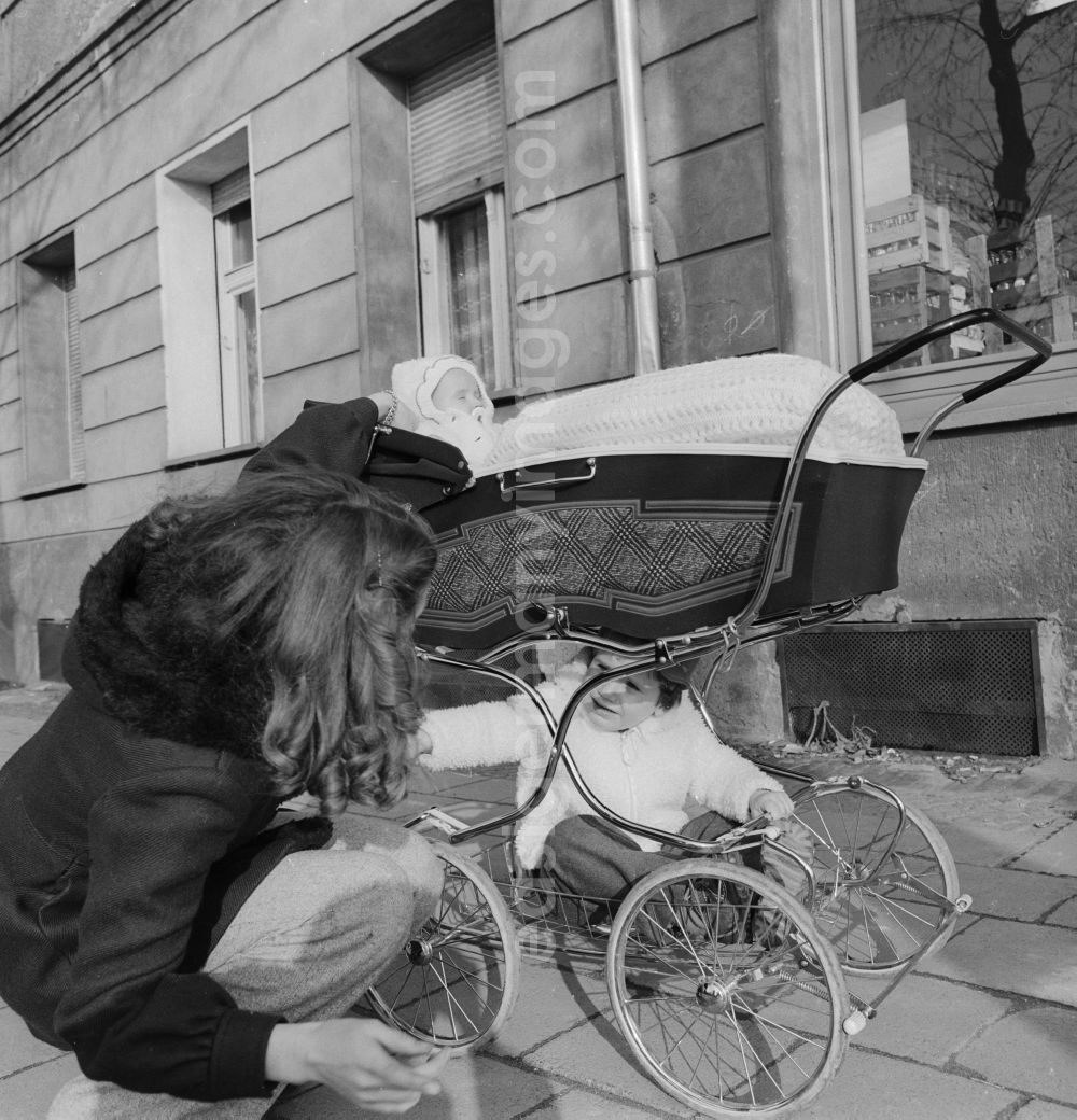 GDR photo archive: Berlin - Young mother with a pram on a walk in Berlin. Above is the baby in the basket and sits below the larger sibling