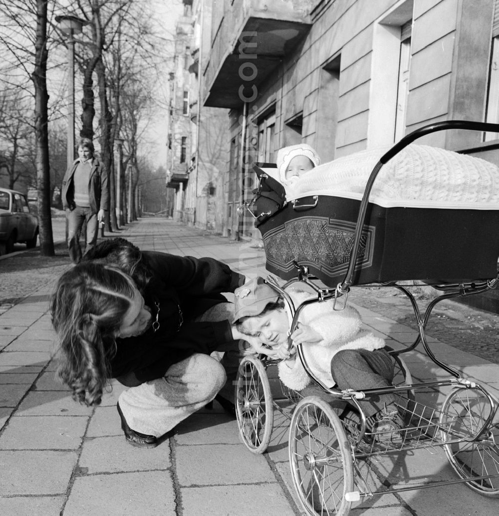 GDR image archive: Berlin - Young mother with a pram on a walk in Berlin. Above is the baby in the basket and sits below the larger sibling