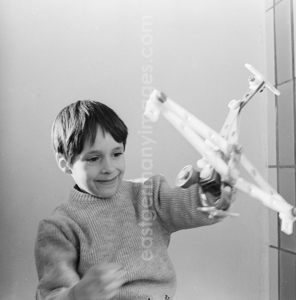 GDR image archive: Berlin - A boy plays with an airplane made of plastic parts in Berlin, the former capital of the GDR, German Democratic Republic