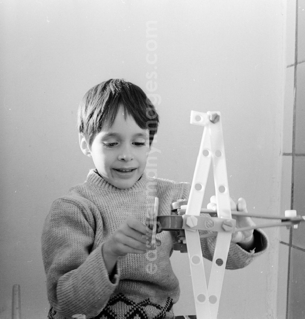 GDR photo archive: Berlin - A boy plays with an airplane made of plastic parts in Berlin, the former capital of the GDR, German Democratic Republic