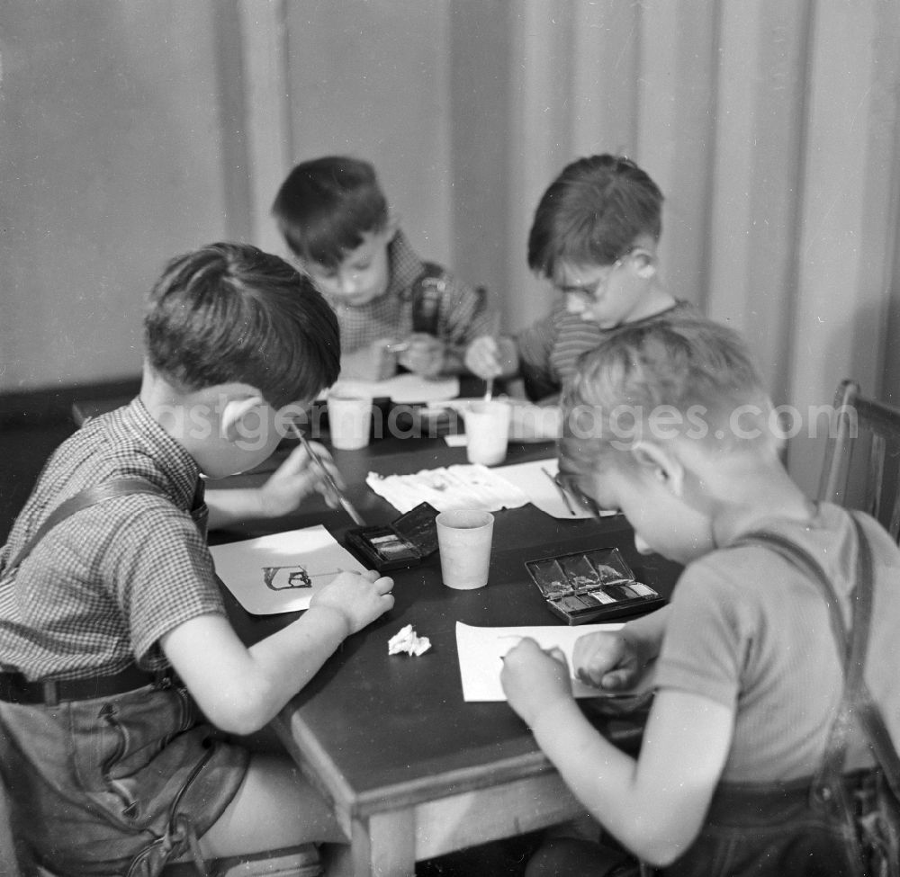 GDR photo archive: Arnstadt - Boys in short leather trousers sit at the table and paint with Indian ink in Arnstadt in the federal state Thuringia in the area of the former GDR, German democratic republic