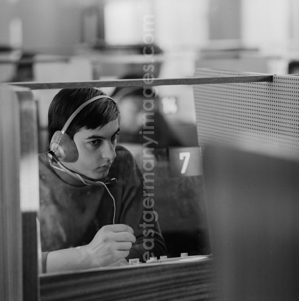 GDR image archive: Berlin - Weißensee - A young man sits in the Cabinet of language in a booth with headphones in Berlin - Weissensee. A speech Cabinet, also called language lab, is a specially equipped room for learning languages??. He is the active exercise of speaking and understanding