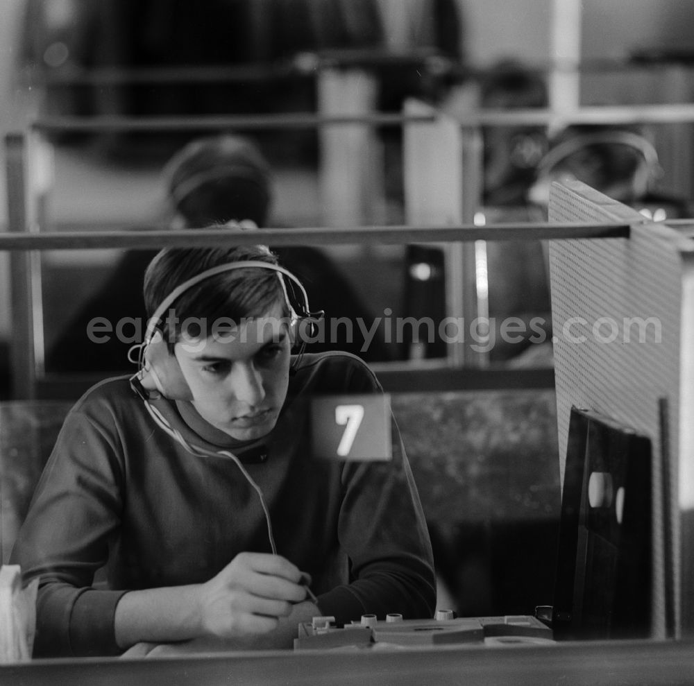 GDR picture archive: Berlin - Weißensee - A young man sits in the Cabinet of language in a booth with headphones in Berlin - Weissensee. A speech Cabinet, also called language lab, is a specially equipped room for learning languages??. He is the active exercise of speaking and understanding
