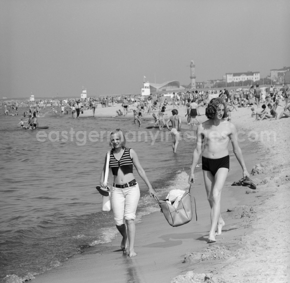GDR photo archive: Warnemünde - Young couple walking barefoot on the beach in the seaside resort of Warnemünde in Mecklenburg - Western Pomerania
