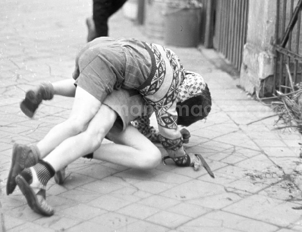 GDR photo archive: Kahla - Auf dem Nachhauseweg von der Schule messen zwei Jungs bei einer kleinen Balgerei auf dem Fußweg ihre Kräfte.
