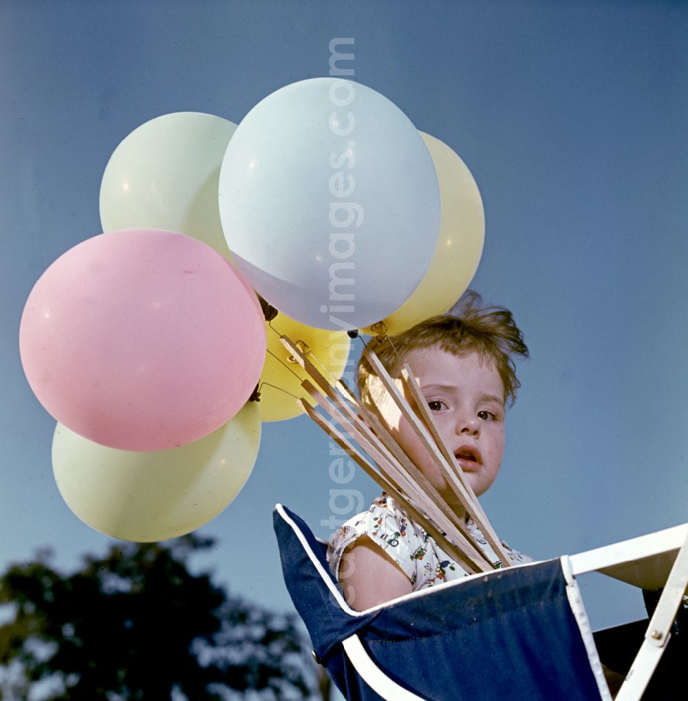 GDR picture archive: Coswig - Girl with balloons in a stroller in Coswig, Saxony in the territory of the former GDR, German Democratic Republic