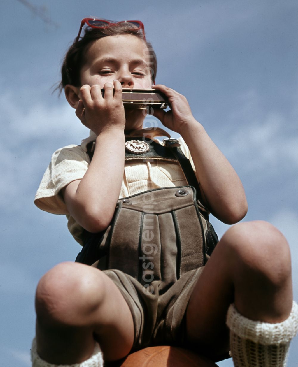 GDR image archive: Coswig - A little boy plays a harmonica in Coswig, Saxony in the territory of the former GDR, German Democratic Republic
