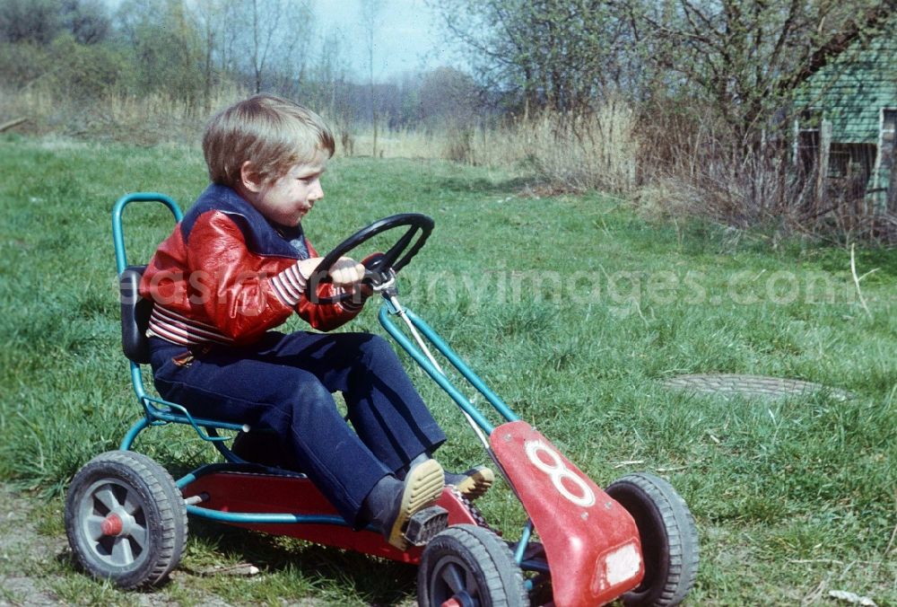 Neustrelitz: A child sits on a pedal car Kettcar in Neustrelitz in the federal state Mecklenburg-West Pomerania in the area of the former GDR, German democratic republic