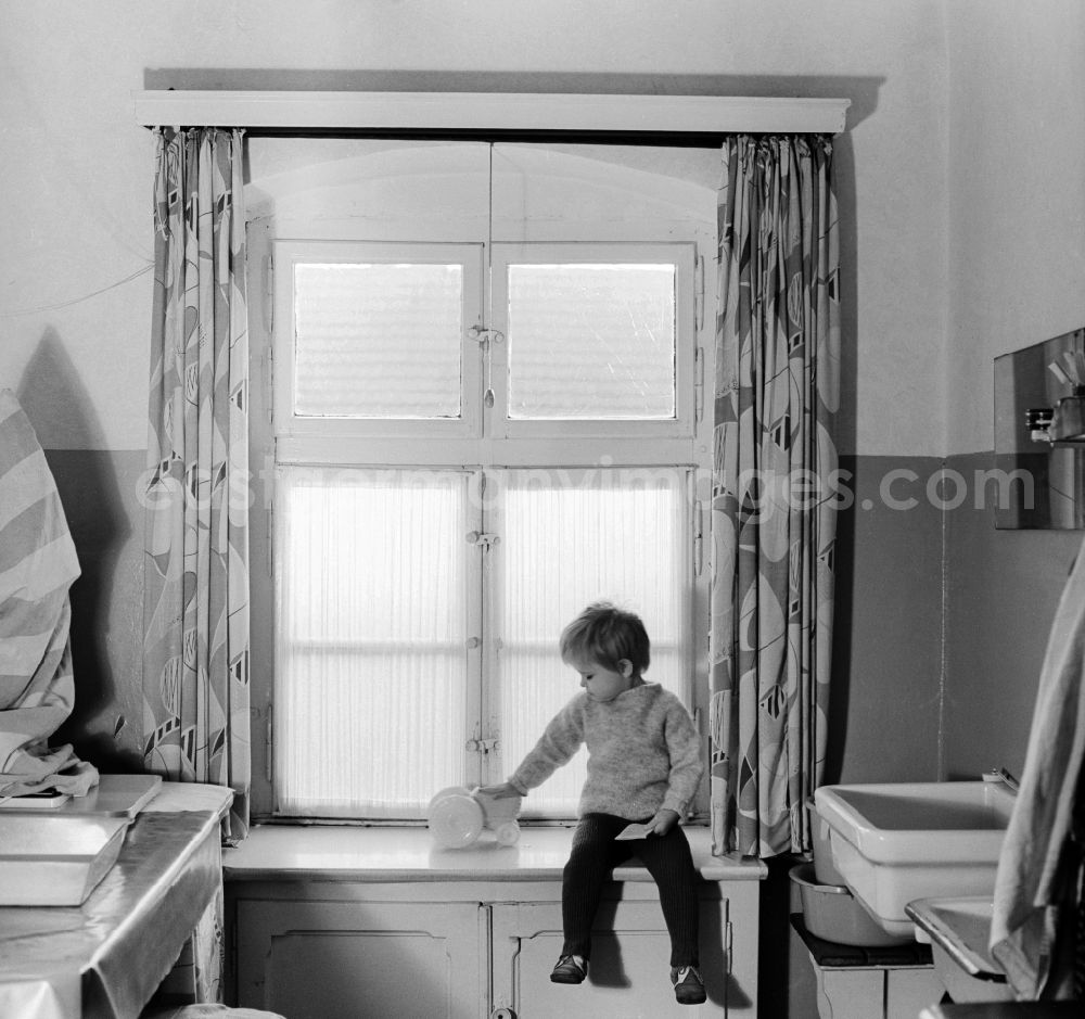 GDR image archive: Berlin - A child sitting on a windowsill with his toys in Berlin, the former capital of the GDR, German Democratic Republic