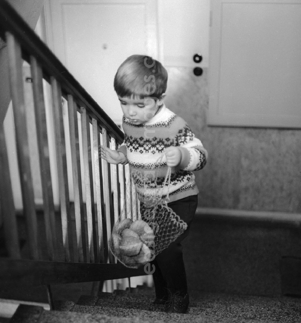 GDR image archive: Berlin - Child carrying a shopping bag with bread rolls in a stairwell in Berlin, the former capital of the GDR, the German Democratic Republic