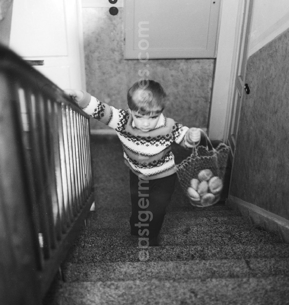 GDR photo archive: Berlin - Child carrying a shopping bag with bread rolls in a stairwell in Berlin, the former capital of the GDR, the German Democratic Republic