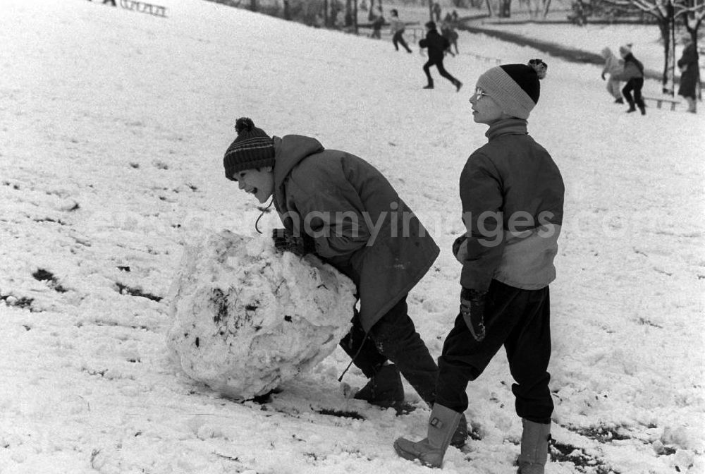 GDR photo archive: Berlin - Zwei Kinder formen Schneekugeln im Volkspark Friedrichshain, um einen Schneemann zu bauen.