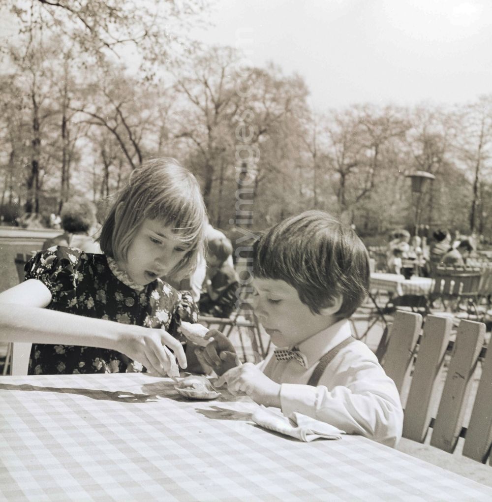 GDR picture archive: Berlin - A brothers and sisters pair / children sit at a table in an open air restaurant and eat an ice in Berlin, the former capital of the GDR, German democratic republic