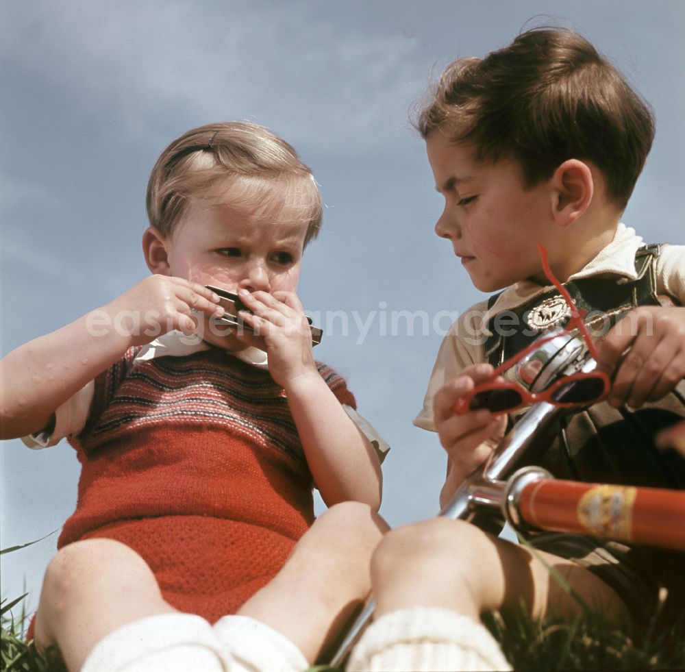GDR photo archive: Coswig - Two boys play with a harmonica and a scooter in Coswig, Saxony in the territory of the former GDR, German Democratic Republic