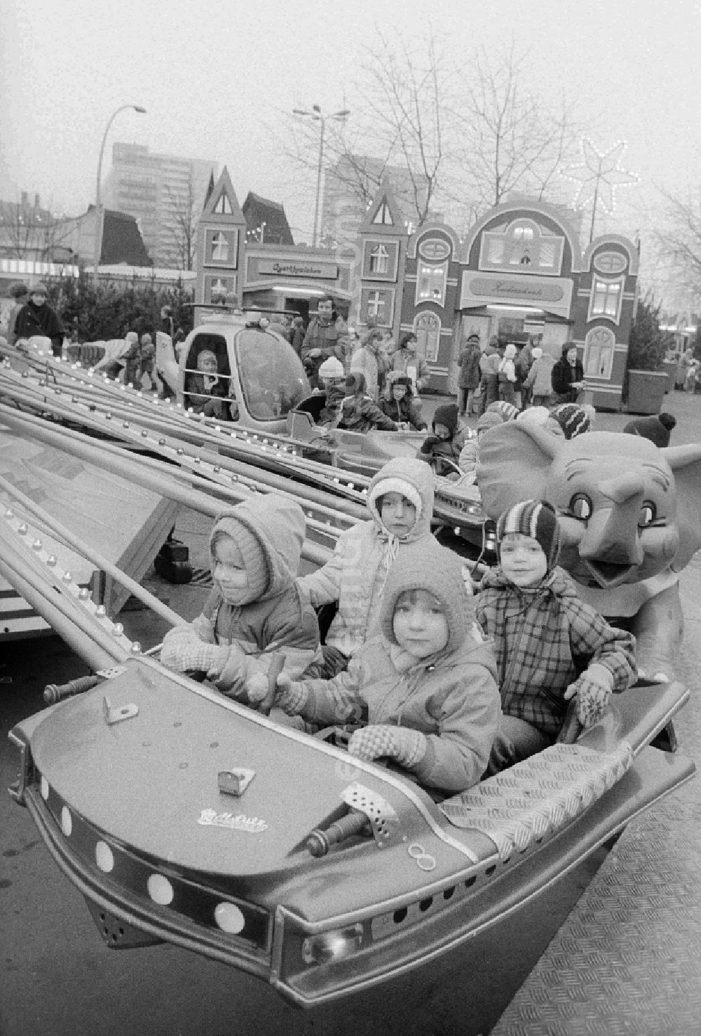 GDR picture archive: Berlin - Children sit in a roundabout on the Berlin Christmas fair in Berlin, the former capital of the GDR, German democratic republic. Today there stands at this point the shopping centre Alexa