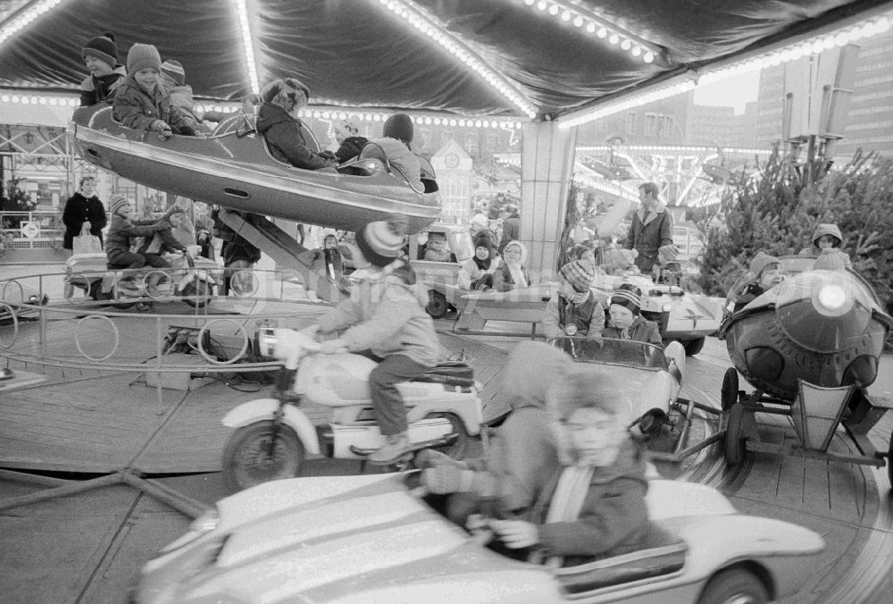 GDR picture archive: Berlin - Children sit in a roundabout on the Berlin Christmas fair in Berlin, the former capital of the GDR, German democratic republic. Today there stands at this point the shopping centre Alexa