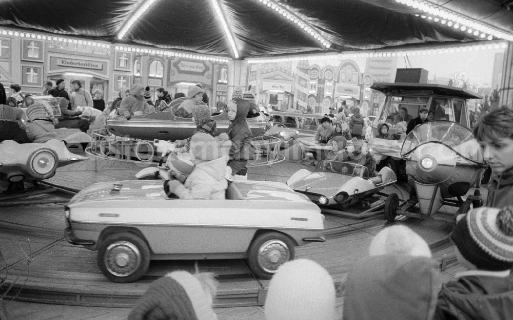 GDR photo archive: Berlin - Children sit in a roundabout on the Berlin Christmas fair in Berlin, the former capital of the GDR, German democratic republic. Today there stands at this point the shopping centre Alexa