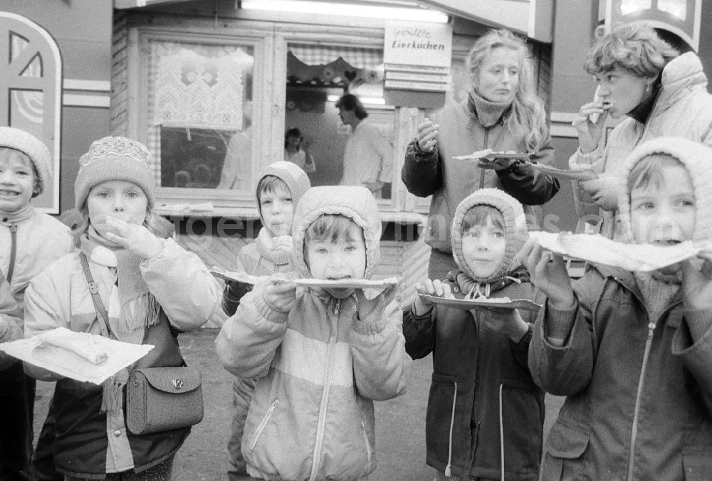 Berlin: Children eat full pancakes on the Berlin Christmas fair in Berlin, the former capital of the GDR, German democratic republic. Today there stands at this point the shopping centre Alexa
