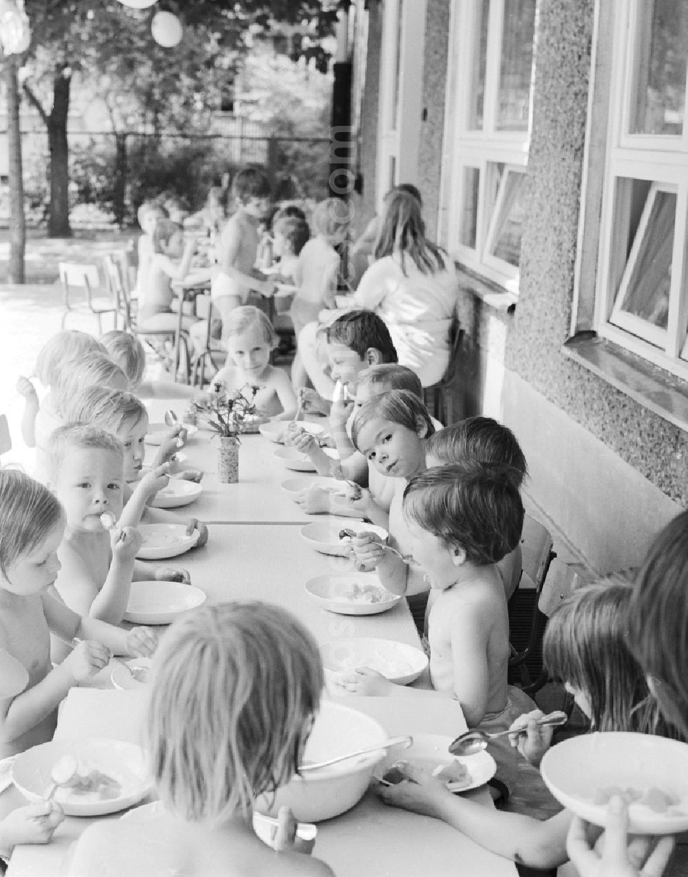 GDR photo archive: Berlin - Children celebrate the International Children's Day at a preschool in Berlin, the former capital of the GDR, German Democratic Republic. On this day there was always a festive program which consisted of sport and play. Here the Community lunch on the terrace