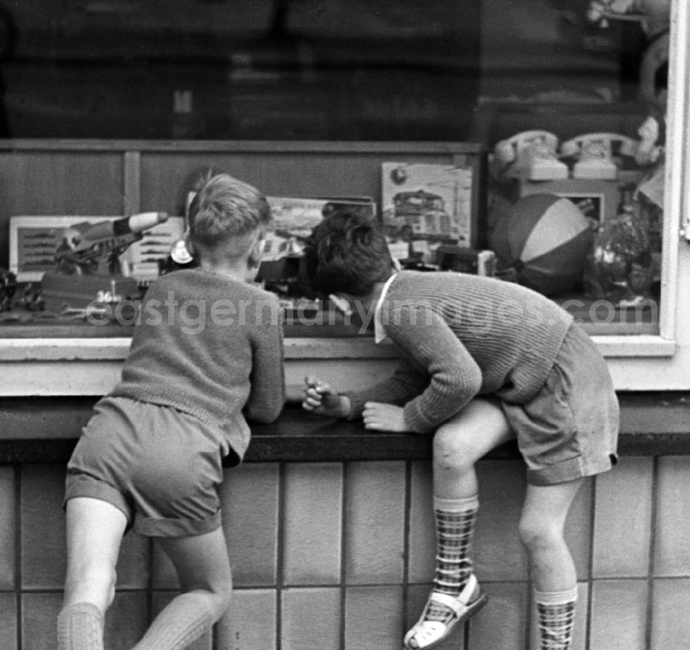 GDR image archive: - Dresden 12.6.1962 Zwei Jungs schauen neugierig durch das Schaufenster eines Dresdner Spielwarengeschäftes. Vor allem die Militärfahrzeuge scheinen ihr Interesse geweckt zu haben.