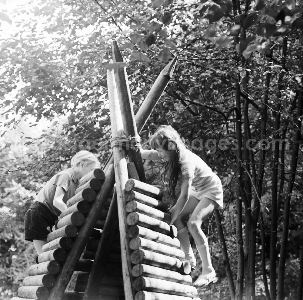 GDR photo archive: Berlin - Children play playfully on a wooden tepee on a playground in Berlin, the former capital of the GDR, German democratic republic