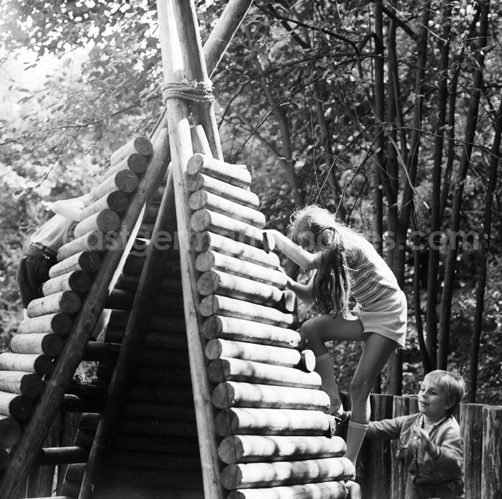 GDR picture archive: Berlin - Children play playfully on a wooden tepee on a playground in Berlin, the former capital of the GDR, German democratic republic