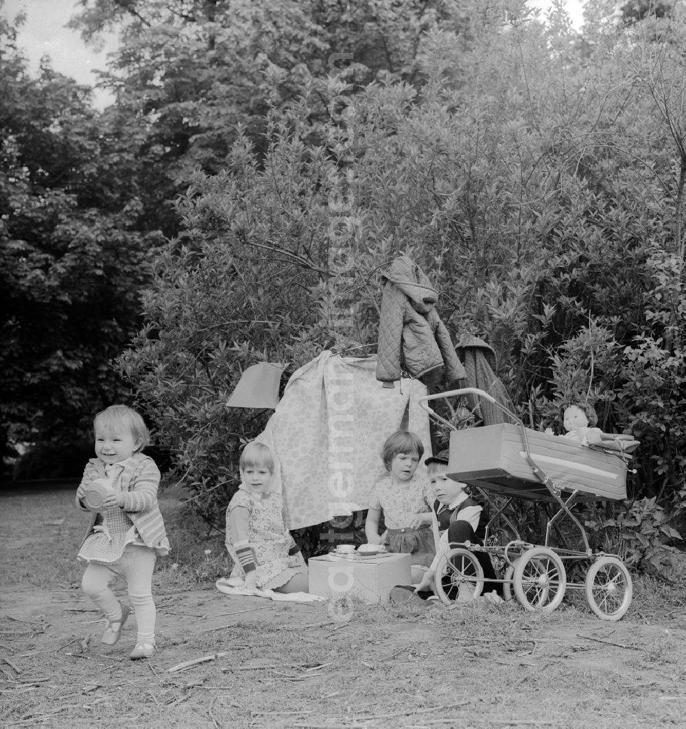 GDR photo archive: Berlin - Children playing mother father child in a garden in Berlin, the former capital of the GDR, German Democratic Republic