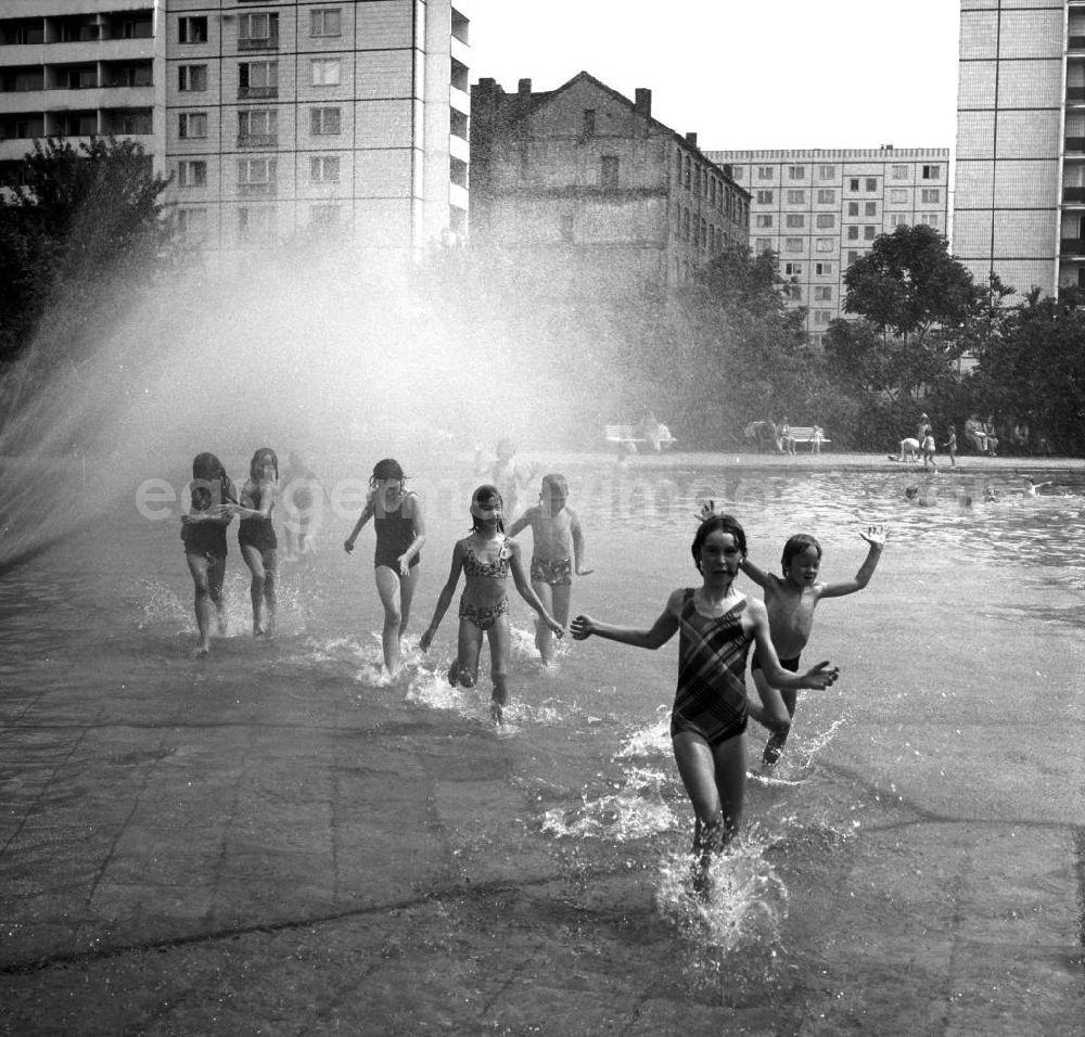 Berlin: Planschbecken / Kinderbad in der Singerstrasse. Kinder laufen durch Planschbecken an Wasserfontäne vorbei.