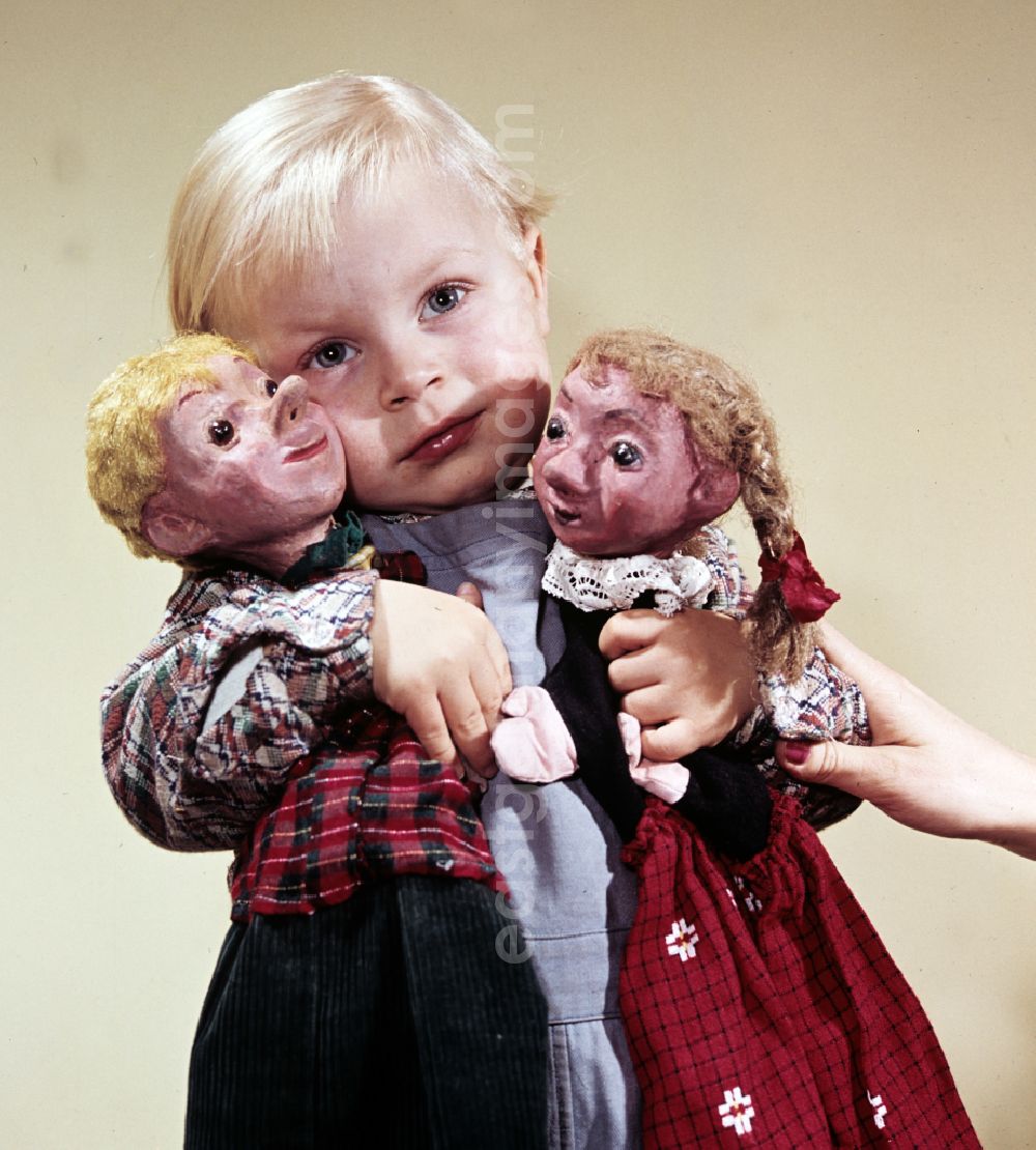 GDR picture archive: Berlin - A boy with blond hair holds the hand puppets Kruemel (girl) and Flax (boy) in East Berlin on the territory of the former GDR, German Democratic Republic