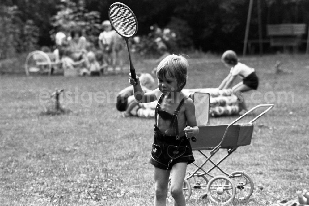GDR picture archive: Berlin - Boy in leather pants plays badminton in kindergarten in Berlin Eastberlin on the territory of the former GDR, German Democratic Republic