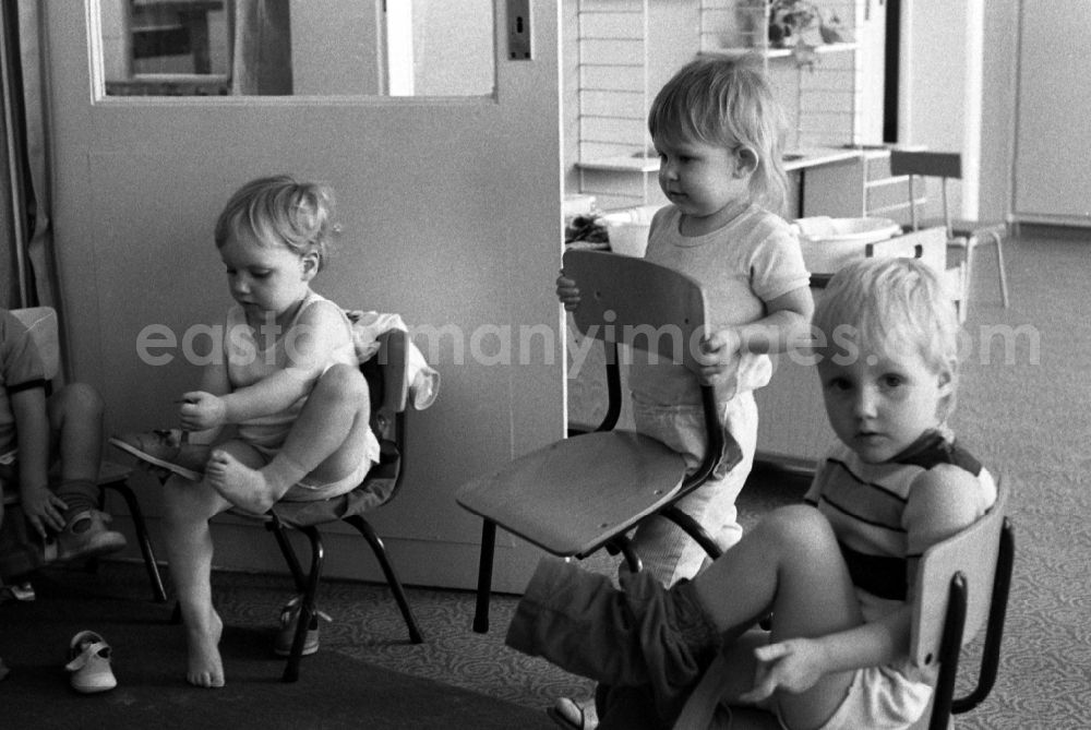 GDR picture archive: Berlin - Preparing for a nap in the kindergarten in Berlin Eastberlin on the territory of the former GDR, German Democratic Republic. Toddlers take off their clothes together