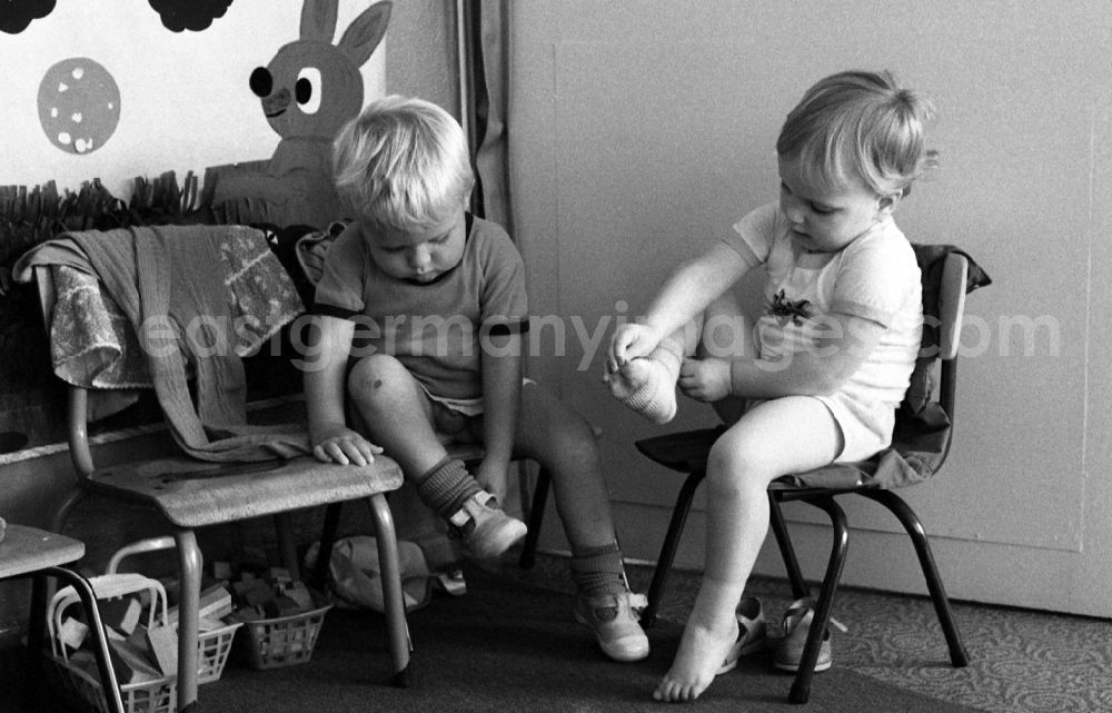 GDR image archive: Berlin - Preparing for a nap in the kindergarten in Berlin Eastberlin on the territory of the former GDR, German Democratic Republic. Toddlers take off their clothes together