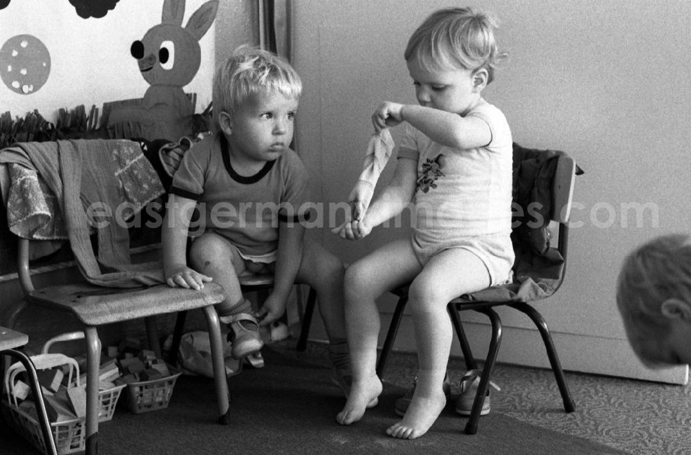 GDR photo archive: Berlin - Preparing for a nap in the kindergarten in Berlin Eastberlin on the territory of the former GDR, German Democratic Republic. Toddlers take off their clothes together