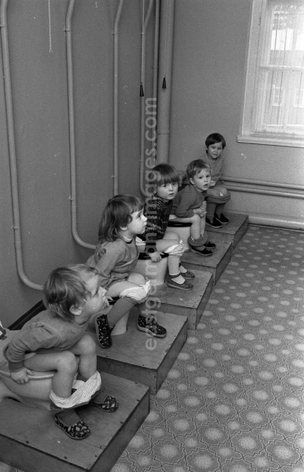 GDR photo archive: Berlin - Small children crouching next to each other in the toilet in a kindergarten in Berlin East Berlin on the territory of the former GDR, German Democratic Republic