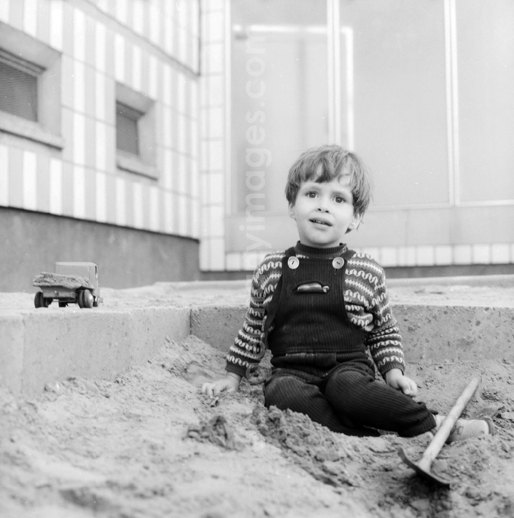 GDR photo archive: Berlin - A small boy in a Kordlatzose plays in the sandpit in Berlin, the former capital of the GDR, German democratic republic