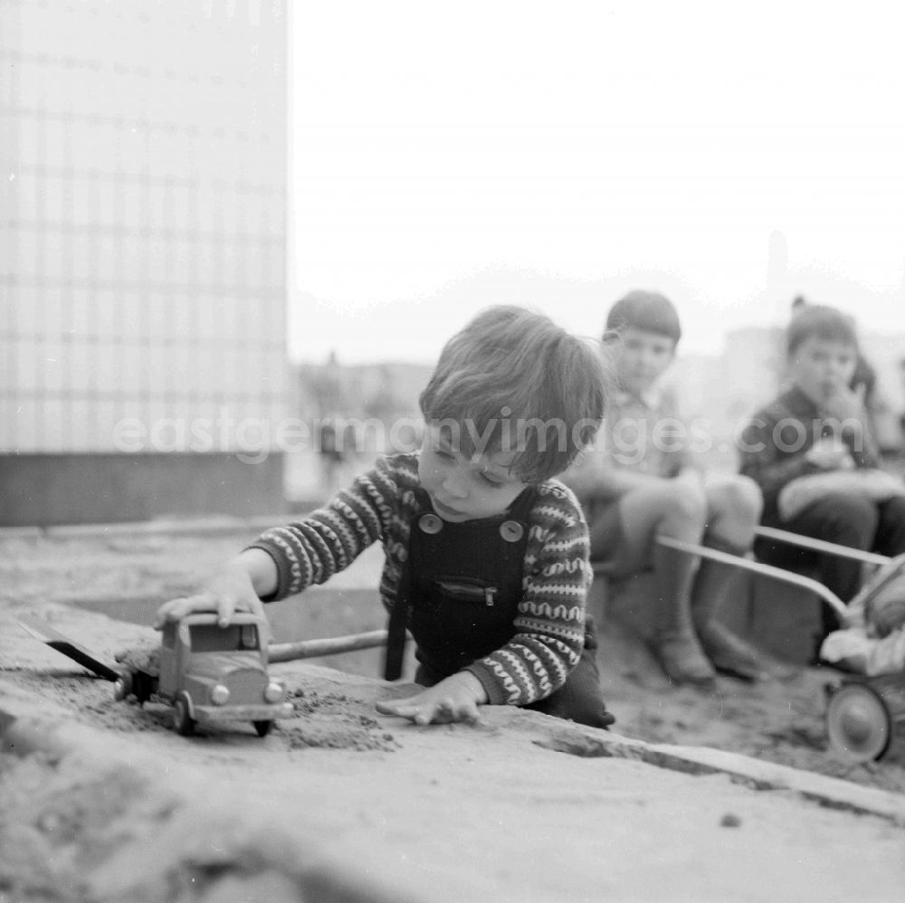GDR photo archive: Berlin - A small boy plays in the sandpit by a toys car in Berlin, the former capital of the GDR, German democratic republic