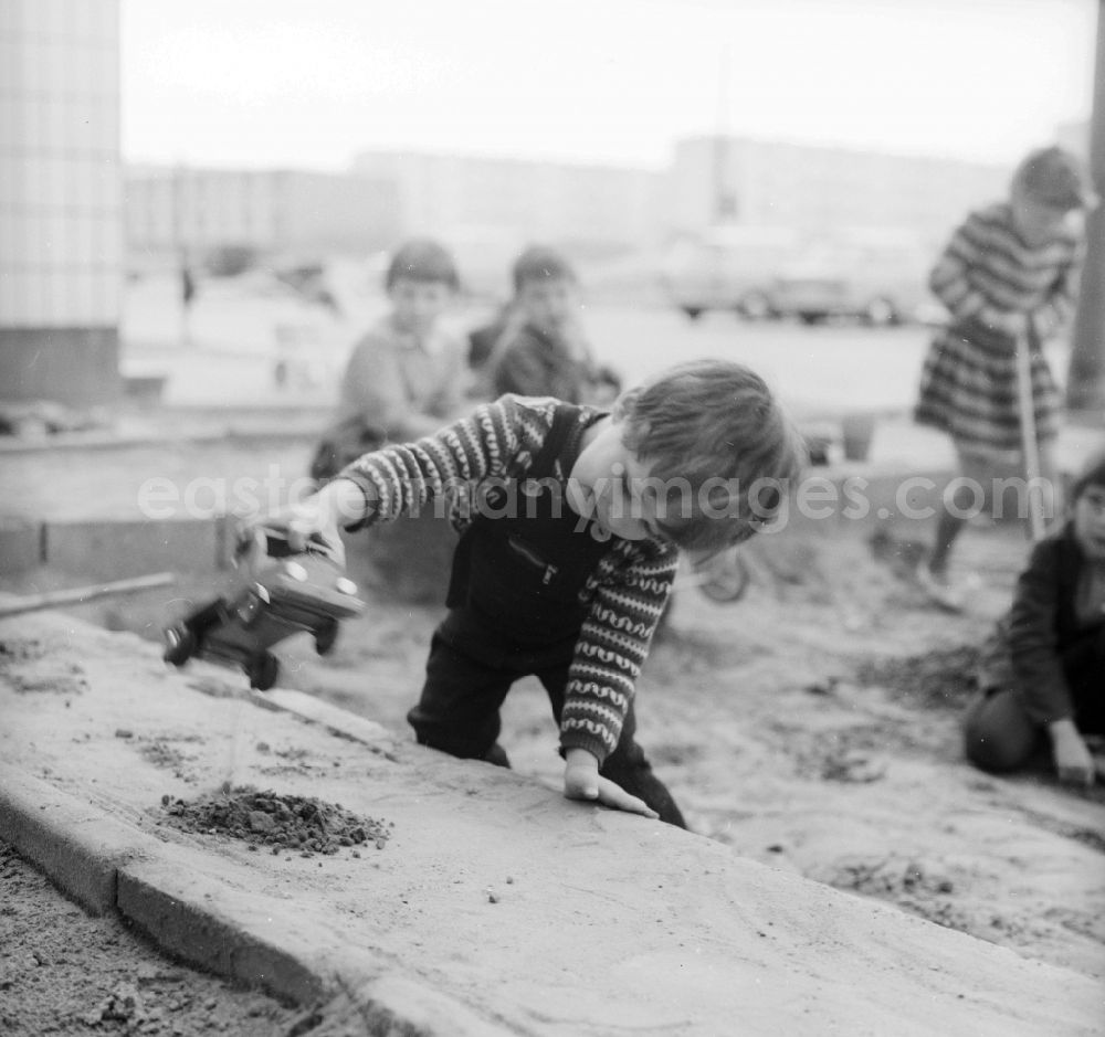 GDR picture archive: Berlin - A small boy plays in the sandpit by a toys car in Berlin, the former capital of the GDR, German democratic republic