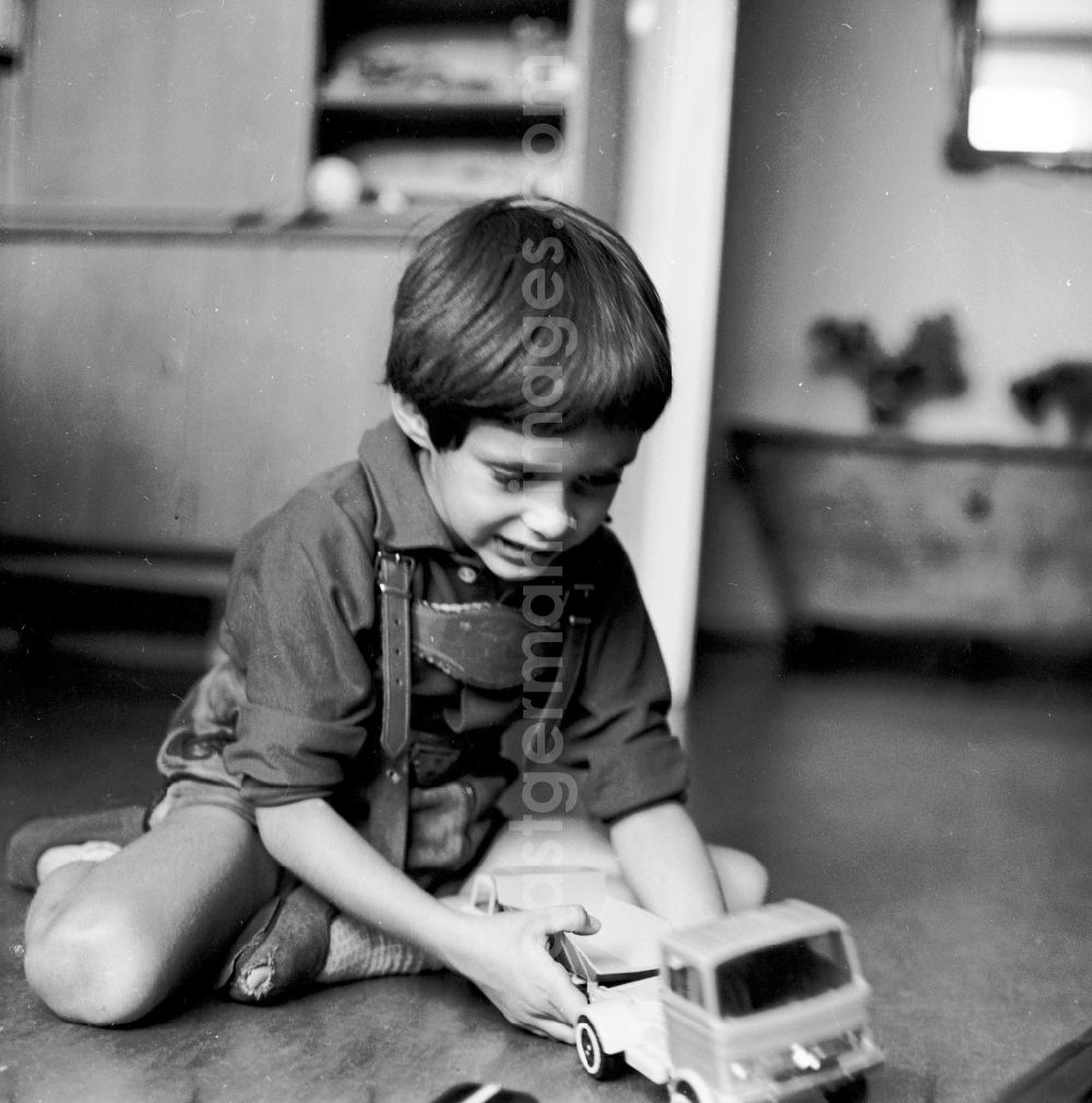 Berlin: A small boy with leather trousers plays by his toys cars on the floor in Berlin, the former capital of the GDR, German democratic republic
