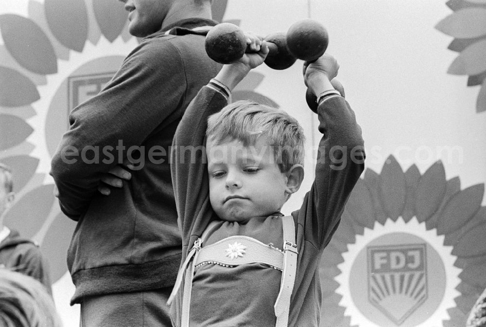 GDR image archive: Chemnitz - A little boy with two dumbbells made of metal at the Whitsun meeting of the FDJ in Karl-Marx-Stadt, today Chemnitz in the federal state Saxony on the territory of the former GDR, German Democratic Republic