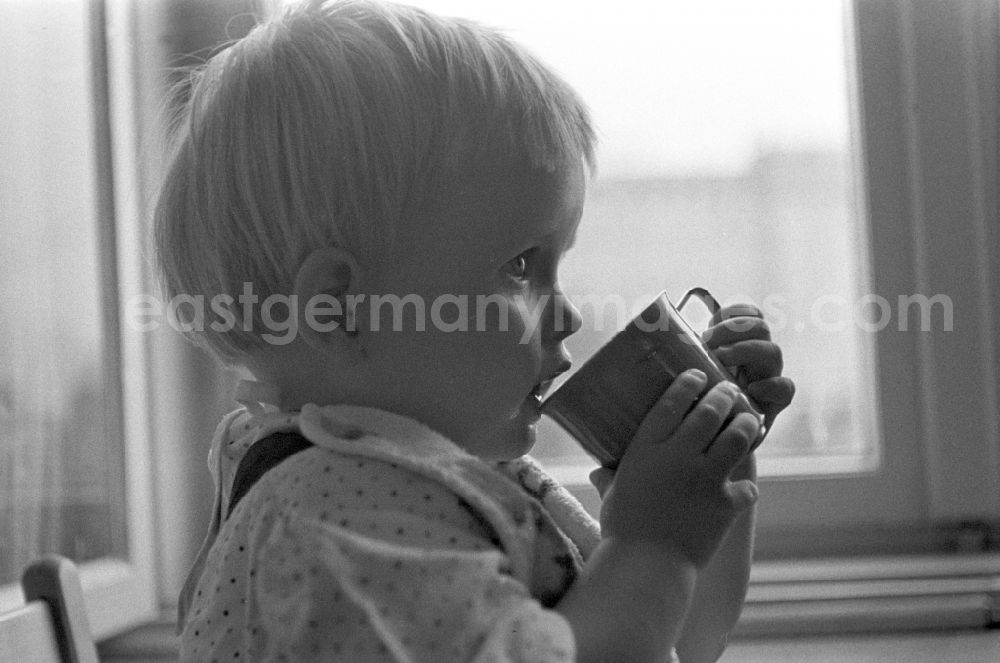 GDR picture archive: Berlin - Friedrichshain - A small child while drinking a cup in Berlin
