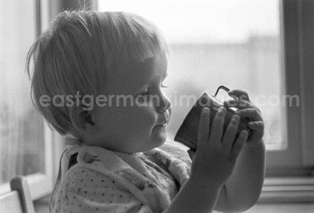 GDR photo archive: Berlin - Friedrichshain - A small child while drinking a cup in Berlin