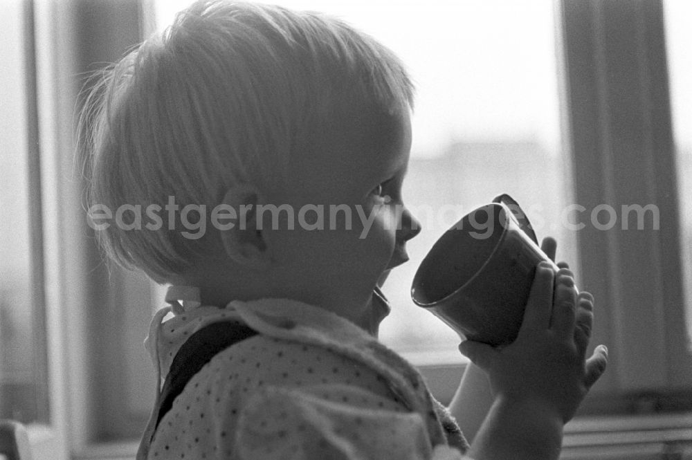 GDR picture archive: Berlin - Friedrichshain - A small child while drinking a cup in Berlin